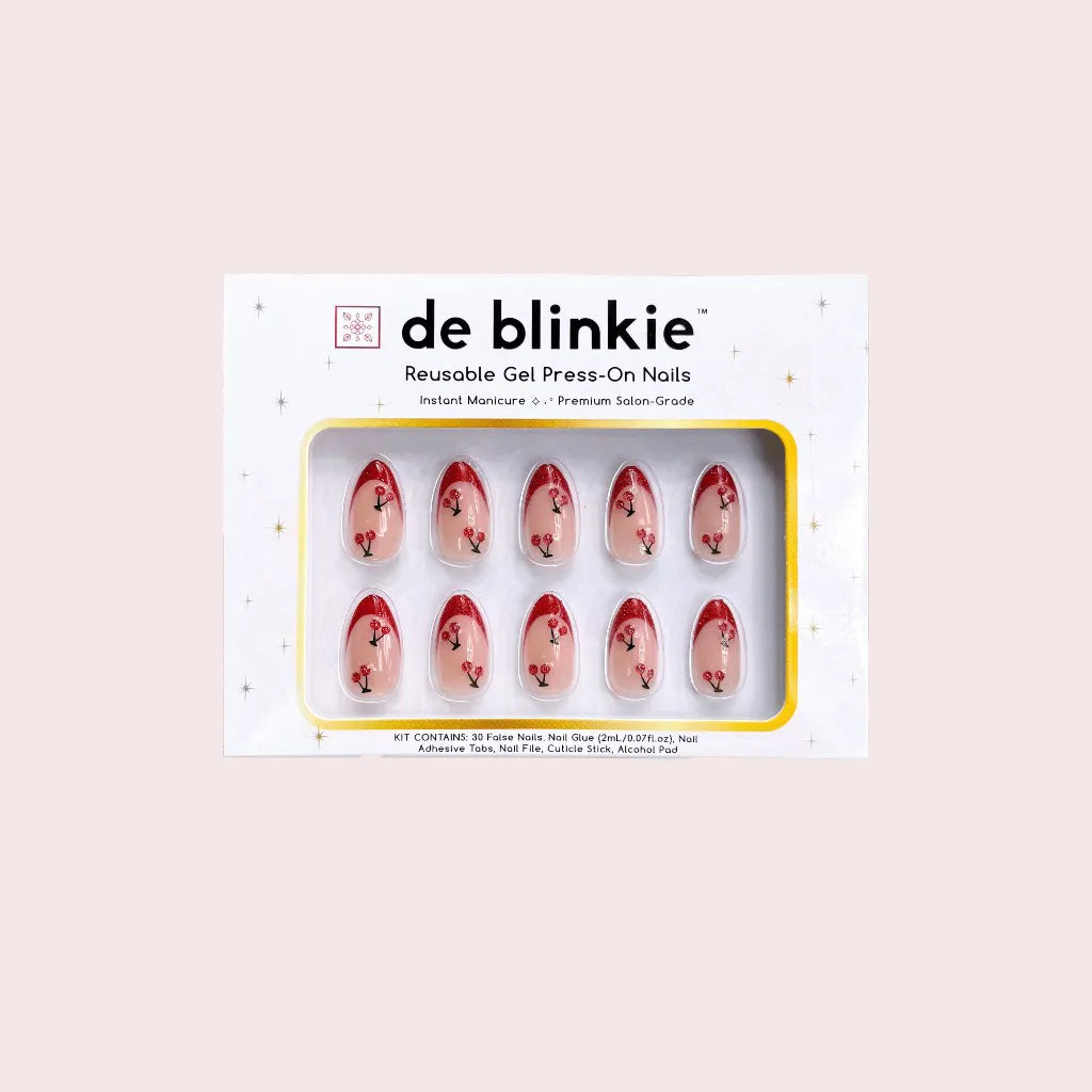 Product box shot showing de blinkie Cherry Blush sheer nude with cherry 3D detail and red glitter tips short almond press-on nails against pink background