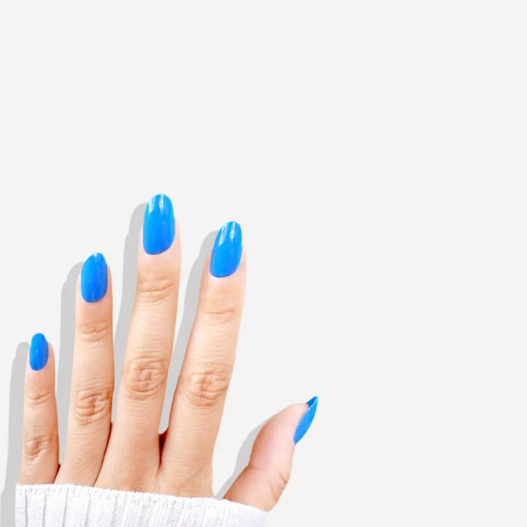 Fingers up pose showing de blinkie Skyline Pop vivid azure blue high gloss press-on nails in short oval shape against white background with white ribbed knit sleeve